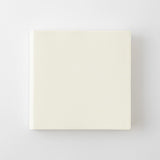 A square cream-colored textured book shown from a top-down perspective on a light gray background.