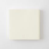 A square cream-colored book with a debossed 'MD' logo at the bottom, shown on a clean white background.