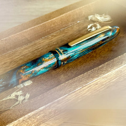 Fountain pen with a decorative blue and gold design on a wooden surface