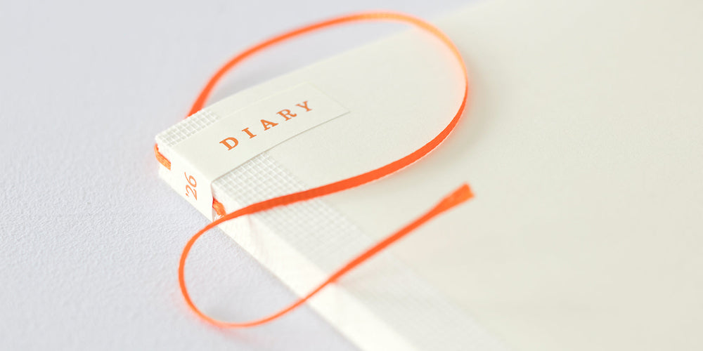 Diary with an orange string on a light gray background