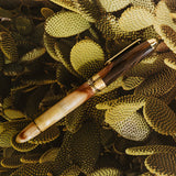 Pen with wooden and bone handle on a textured green surface