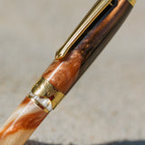 Close-up of a wooden pen with gold accents on a neutral background