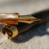 Close-up of a gold fountain pen nib on a textured surface