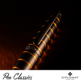 A close up image of the black clip of a Diplomat Elox Fountain Pen Ring Black/Orange on a wooden background